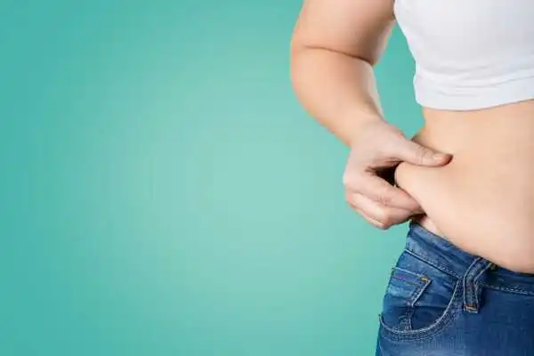 Image of woman pinching her love handles to show weight gain Billericay